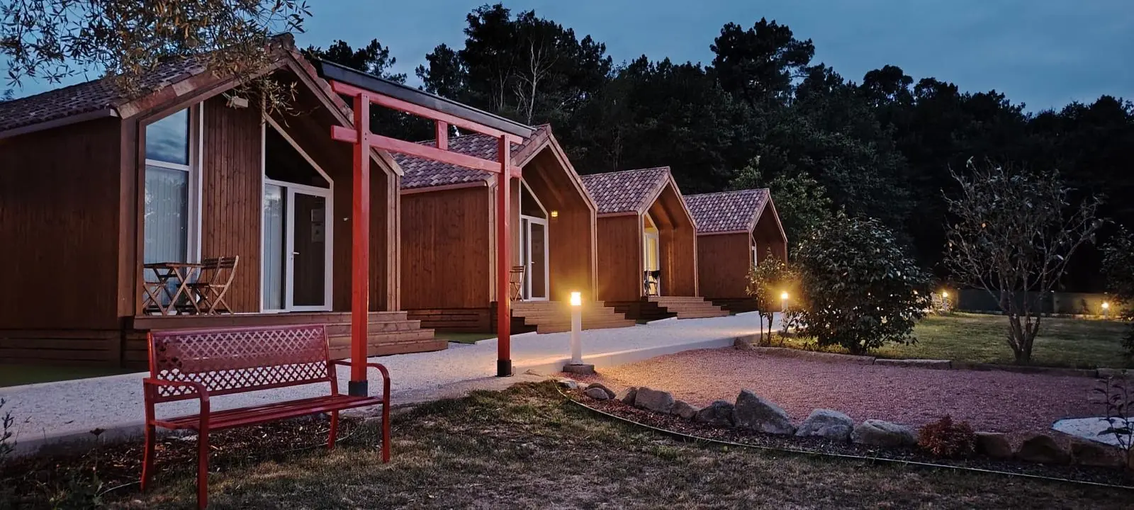 Cabañas de madera de As Cabanas do río Pego iluminadas al anochecer
