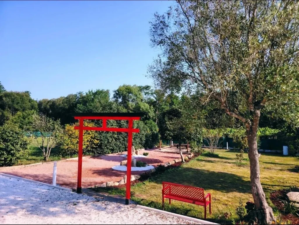 Jardín japonés con torii rojo y banco en As Cabanas do río Pego, Brión