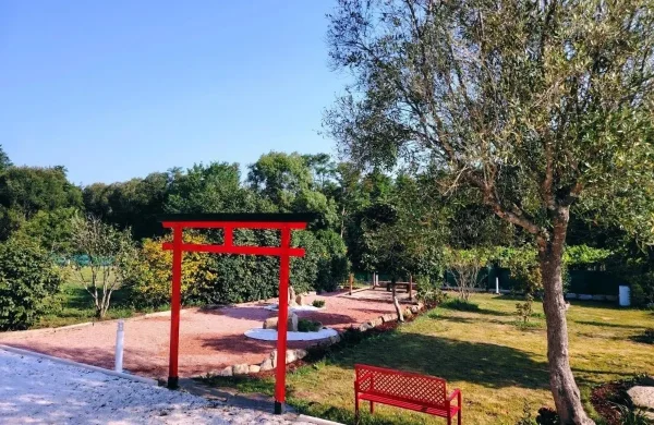 Jardín japonés con torii rojo, banco y rocalla en As Cabanas do río Pego, Brión
